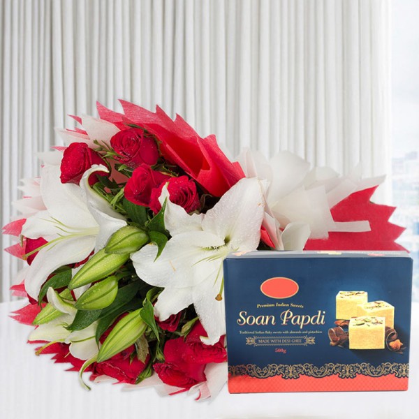 A bunch of Flowers (12 Red Roses, 3 White Asiatic Lily) in Red and White Paper Packing, White Paper Bow with Soan Papdi (Half Kg)